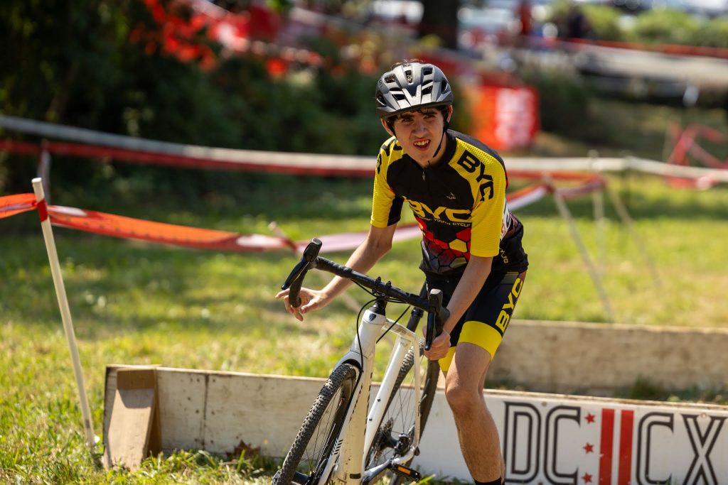 Photo of a biker running with their bike just in front of a barrier