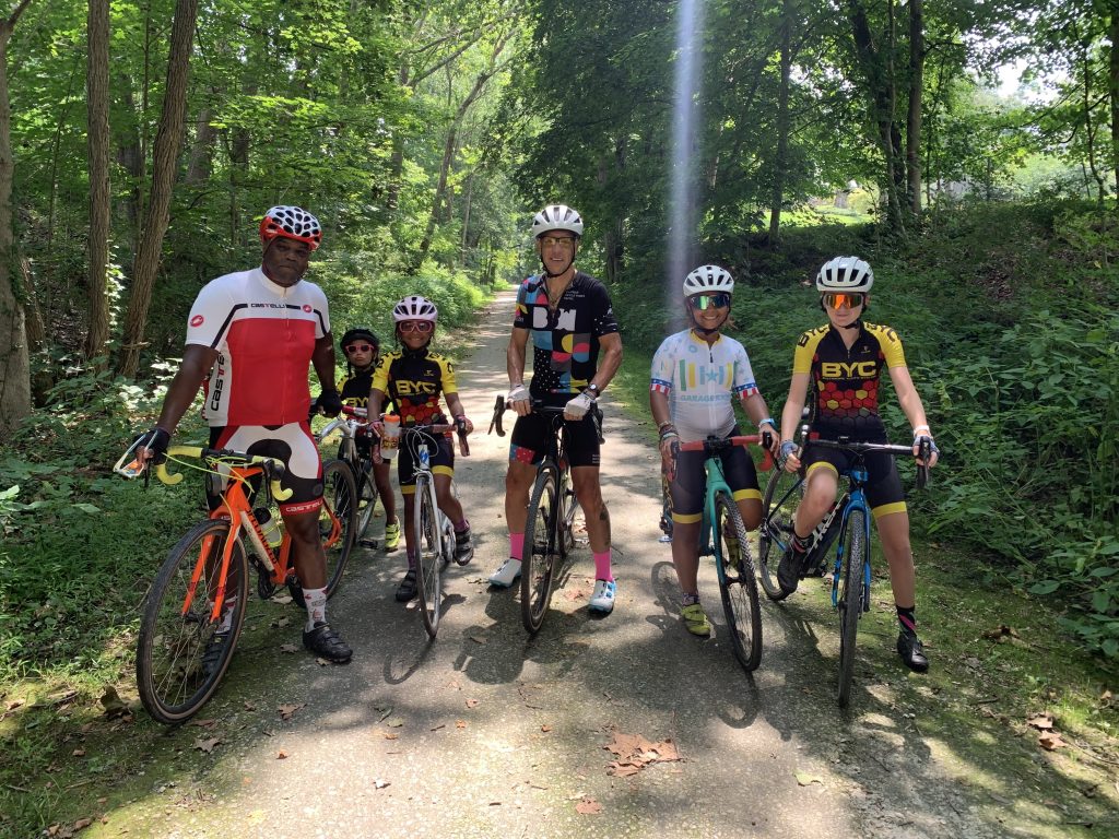 Photo of two adults and four kids all on bikes posing on a forested trail