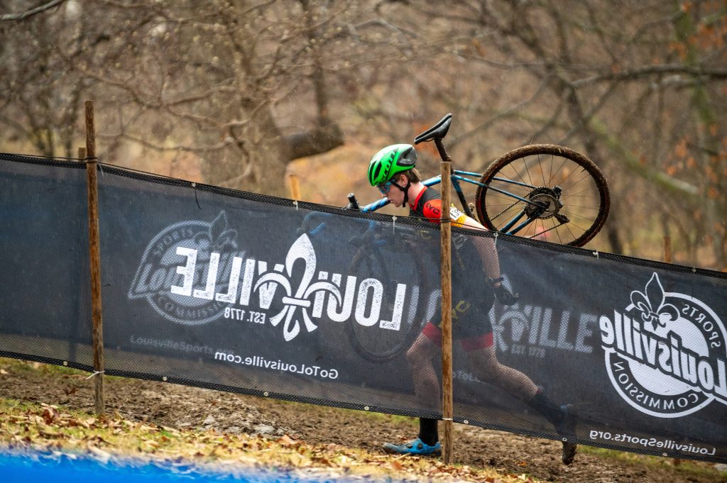 Photo of a racer carrying their bike on their shoulder as they run