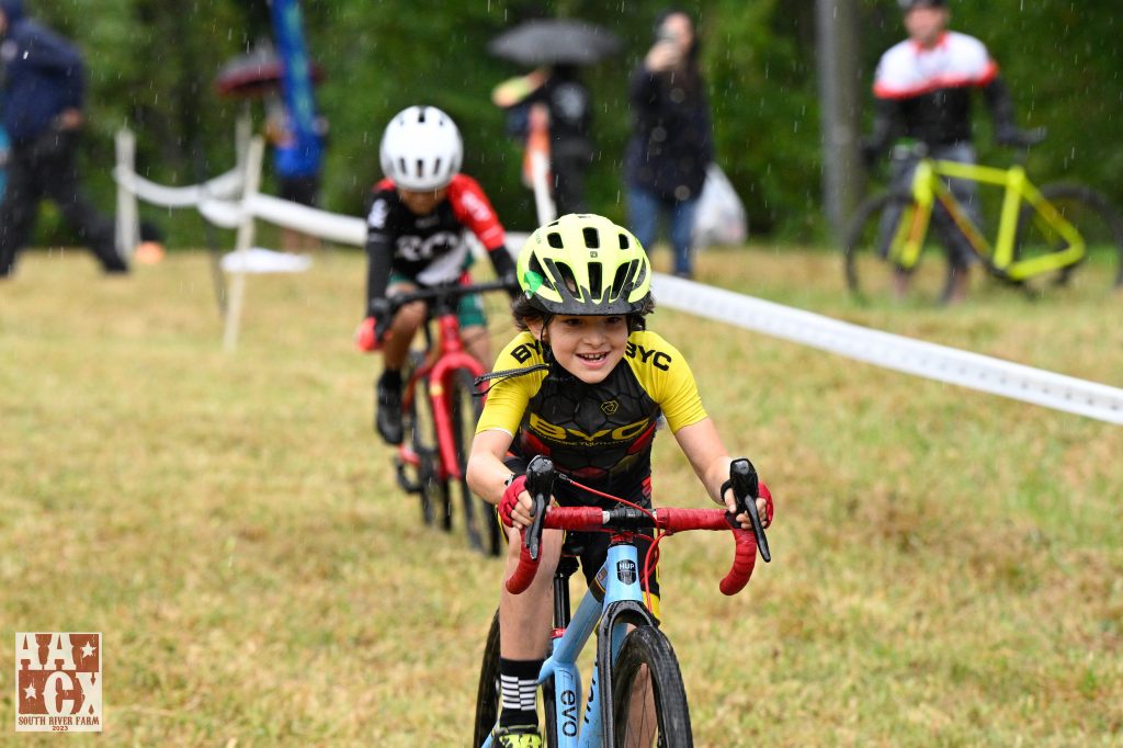 Photo of a grinning kid riding a bike through the rain